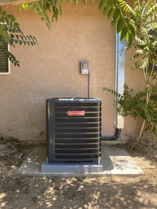 Goodman condensing unit installed beside a stucco wall with electrical disconnect and refrigerant line set at a High Desert home.