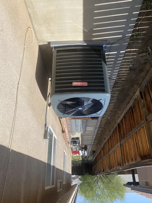 New Goodman AC condenser running in a narrow side yard along a block wall at a High Desert residence.
