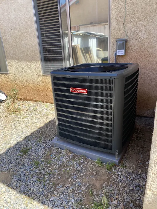 New Goodman AC condenser installed on a gravel pad along the side yard of a High Desert home.