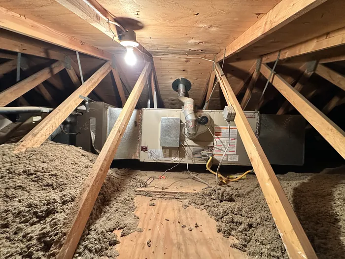 Horizontal attic gas furnace with flue vent and electrical whip surrounded by blown-in insulation in a High Desert residence.