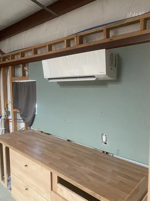 Daikin wall-mounted ductless mini-split indoor head installed on a green wall inside a wood-framed High Desert room with new flooring.